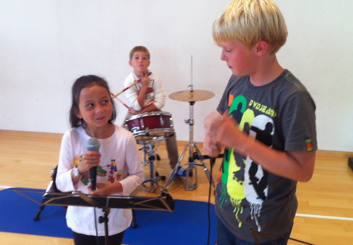 drei Schüler/innen üben einen Rap mit Schlagzeug ein